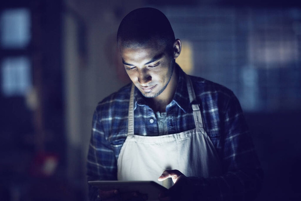 Zijn rooster van de week bijwerken. een jonge man die overwerkt op een digitale tablet in zijn koffieshop - Foto, afbeelding