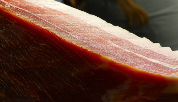detail van een stuk rauwe ham te koop in de delicatessen - Foto, afbeelding