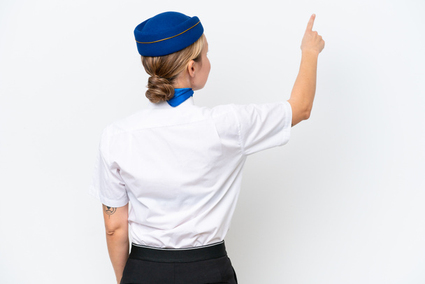 Αεροπλάνο ξανθιά αεροσυνοδός γυναίκα απομονωμένη σε λευκό φόντο δείχνοντας πίσω με το δείκτη - Φωτογραφία, εικόνα