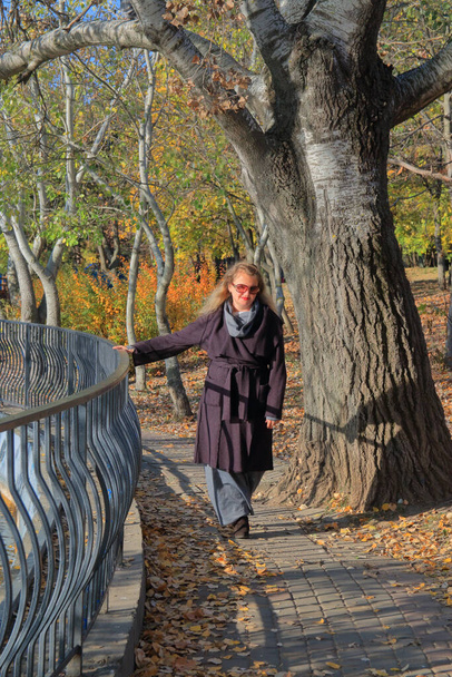 Η φωτογραφία τραβήχτηκε στο δημόσιο πάρκο της Οδησσού, το Πάρκο της Νίκης. Η φωτογραφία δείχνει μια νεαρή γυναίκα να περπατάει κοντά στη λίμνη στο πάρκο του φθινοπώρου. - Φωτογραφία, εικόνα