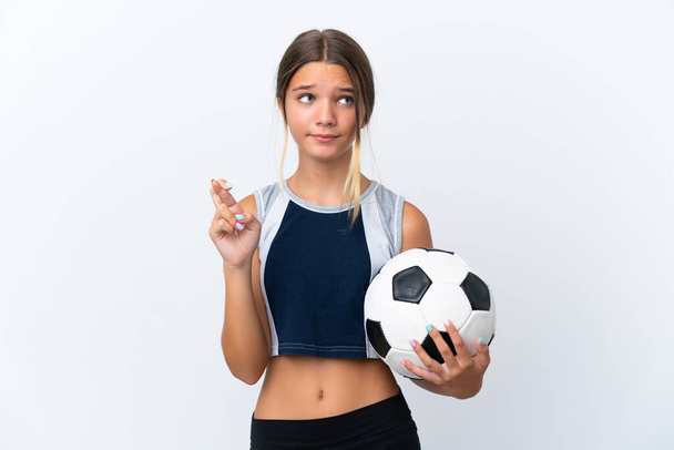 Piccola ragazza caucasica giocare a calcio isolato su sfondo bianco con le dita incrociate e augurando il meglio - Foto, immagini
