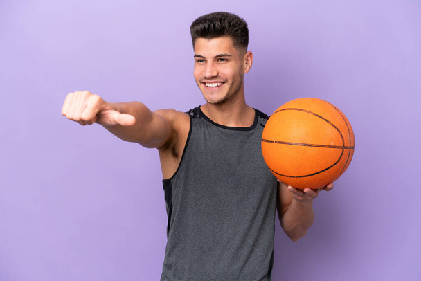 joven caucásico mujer baloncesto jugador hombre aislado en púrpura fondo dando un pulgar hacia arriba gesto - Foto, Imagen