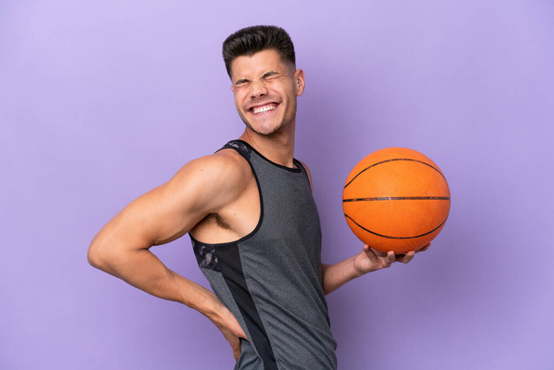 young caucasian woman  basketball player man isolated on purple background suffering from backache for having made an effort - Photo, Image