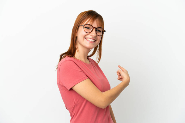 Redhead girl isolated on white background pointing back - Valokuva, kuva