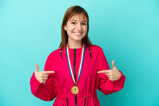 Zrzka dívka s medailemi izolované o modré pozadí hrdý a self-spokojen - Fotografie, Obrázek