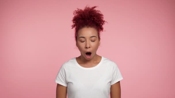 Porträt schockiert afroamerikanische rothaarige Lockenkopf Frau Kamera mit offenem Mund. Aufgeregte Frau in weißem T-Shirt steht auf isoliertem rosa Hintergrund mit Kopierraum. Menschen emotionalisieren Lebensstil - Filmmaterial, Video