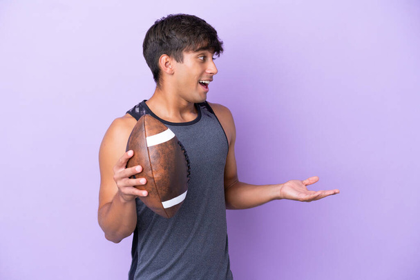 Young man playing rugby isolated on purple background with surprise expression while looking side - Photo, Image