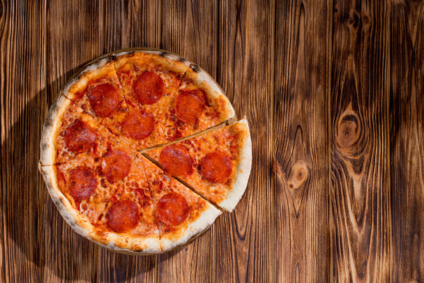 Pizza with tomato sauce, mozzarella, salami on wood background. View from above, copy space. - Valokuva, kuva