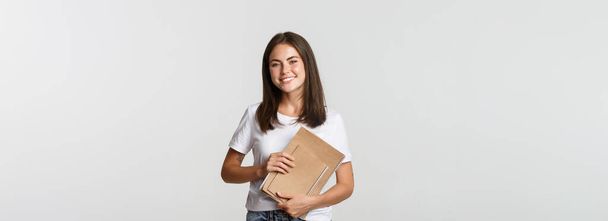 Щаслива усміхнена студентка, яка тримає ноутбуки, подає заявку на курси або університет
. - Фото, зображення