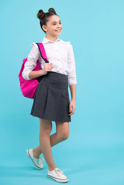 Back to school. Teenager schoolgirl in school uniform with backpack. School children on blue isolated studio background - Foto, afbeelding