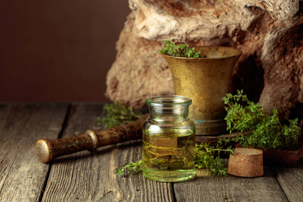 Bottle of thyme essential oil with fresh thyme twigs on an old wooden table. Copy space. - Zdjęcie, obraz