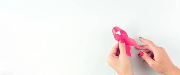 Cancer awareness. Health care symbol pink ribbon in woman hands on white background. Breast woman support concept. World cancer day - Photo, image