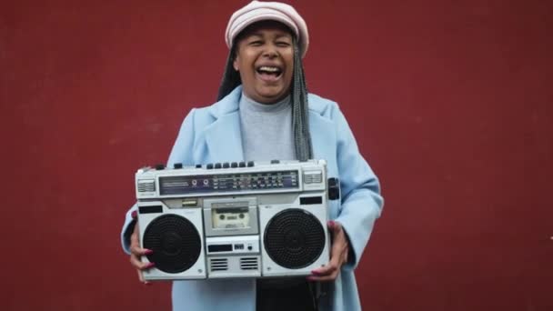 Glücklich trendige ältere afrikanische Frau hat Spaß beim Tanzen, während sie Vintage-Boombox-Stereoanlage hält - Filmmaterial, Video