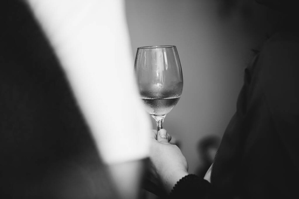 Sklenice bílého vína v držení osoby na prvotřídní degustaci vína s přáteli a blízkými. - Fotografie, Obrázek