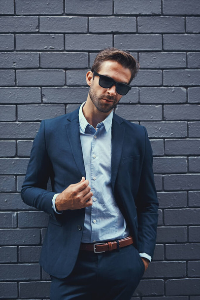 When you look good, you feel good. Portrait of a handsome young businessman standing against a grey facebrick wall - Фото, изображение