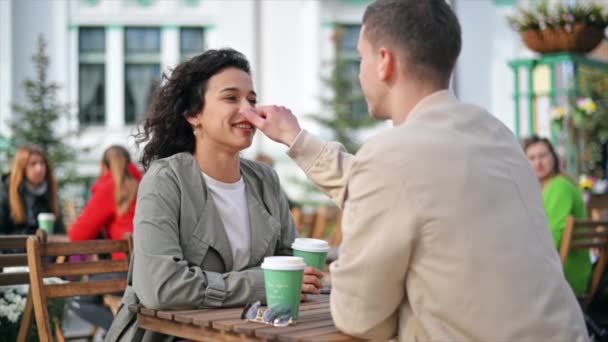 Una pareja feliz al aire libre cerca de un café. Mirándonos el uno al otro, sonriendo y hablando, café. Ambiente otoñal. Movimiento lento - Metraje, vídeo