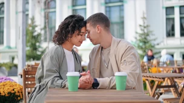 Um casal romântico ao ar livre perto de um café. De mãos dadas, a sorrir, café na mesa. Atmosfera de outono. Movimento lento - Filmagem, Vídeo