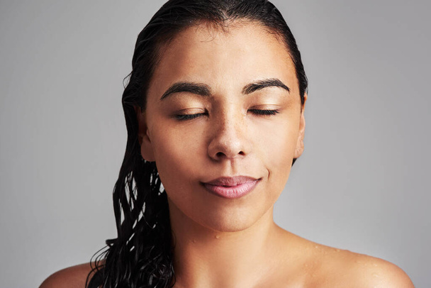 Sie definieren Ihre Schönheit. Studioaufnahme einer jungen Frau mit nassen Haaren, die vor grauem Hintergrund posiert - Foto, Bild