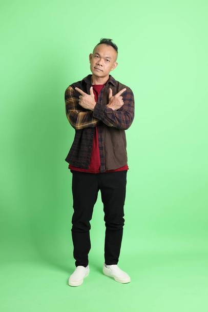 The 40s adult Asian man with plaid shirt standing on the green background. - Fotó, kép