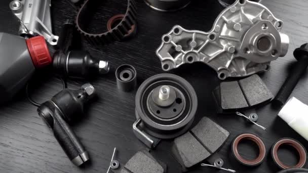 Lot of auto parts lie on wooden black background. Engine and suspension parts, swivel knuckle, joint and engine parts unfolded. New spare parts. Bearings . Play by light. Hanging on table. - Footage, Video