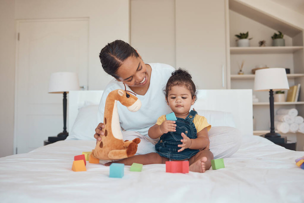 Mother, baby and toys for learning, education and development with building blocks and teddy bear on a bed in a home bedroom. Woman and child together for bonding, love and support while playing. - Zdjęcie, obraz