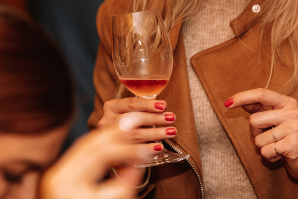 Bicchiere di vino rosato tenuto da una persona in una degustazione di vini premium con amici e cari. - Foto, immagini