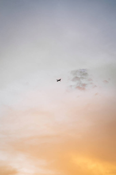 Goldener Himmel bei Sonnenuntergang mit einem kleinen Flugzeug, das hoch fliegt. Flieg zu deinen Träumen Konzepttapete. Glückliche Touristen unterwegs. - Foto, Bild