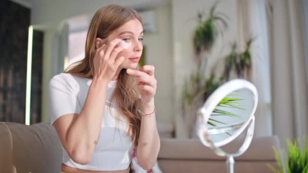 Une jeune femme caucasienne tenant un produit de soins de la peau et regardant dans la caméra - Séquence, vidéo