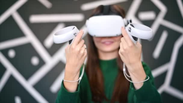 Une jeune femme intéressée à jouer à des jeux VR en utilisant des lunettes VR et des contrôleurs. Mouvement lent - Séquence, vidéo
