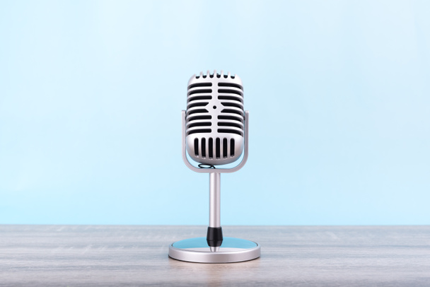 Retro mikrofonu Umieścić na drewnianym stole izolowane na niebieskim tle. - Zdjęcie, obraz