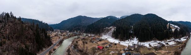 Viaduct railway bridge in the Carpathians of Ukraine, a view of the bridge from a height, a winter panorama of a village in the mountains. - Photo, Image