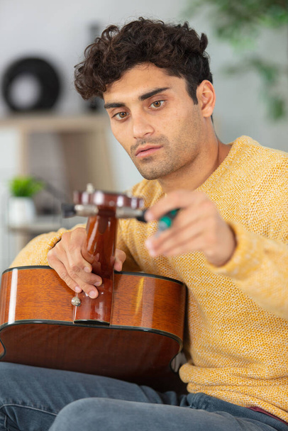 male musician tuning an acoustic guitar - Foto, Bild