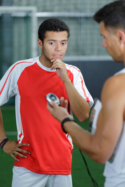 football player looking disappointed as coach reveals time on stopwatch - Foto, afbeelding