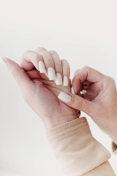 Closeup of the hands of a young woman receiving the nail file by a beautician at the beauty salon. Manicure procedure, nail care and grand opening. Quarantine is over, millennial woman in protective. - Foto, afbeelding