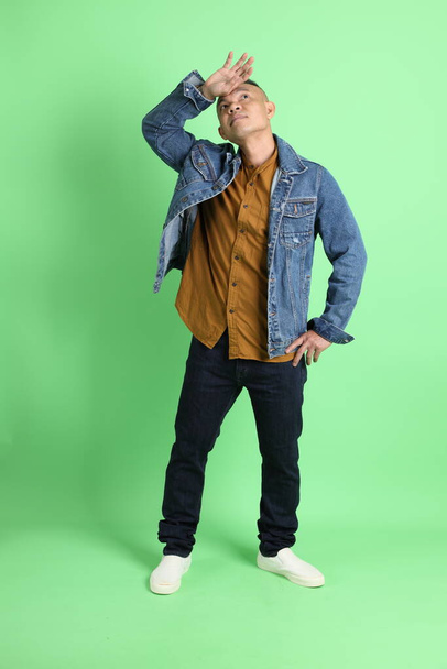 The 40s adult Asian man with jean shirt standing on the green background. - Foto, Imagen