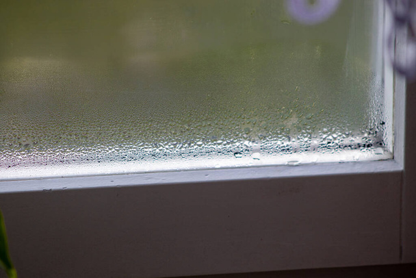 Вікно з конденсатом або парою після сильної текстури дощу. Краплі конденсату і чорної форми на нестандартному металопластиковому вікні
 - Фото, зображення