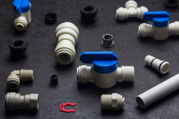Detail of plastic plumbing, air product, pipe and tools. Valves, elbow and tee with locking clip on black background. Fitting industry - Foto, Imagem