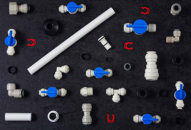 Top view photo of plastic plumbing, air product, pipe and tools. Valves, elbow and tee with locking clip on black background. Fitting industry - Photo, Image