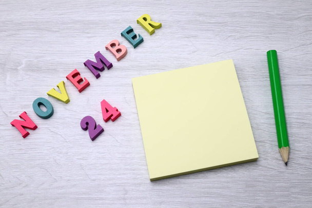 November  24  - Daily colorful Calendar with Block Notes and Pencil on wood table background, empty space for your text or design - Fotó, kép