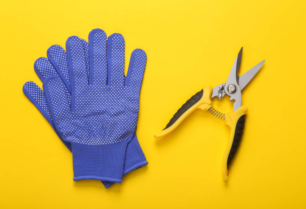 Potatore da giardino con guanti da lavoro su fondo giallo. posare piatto. vista dall'alto - Foto, immagini