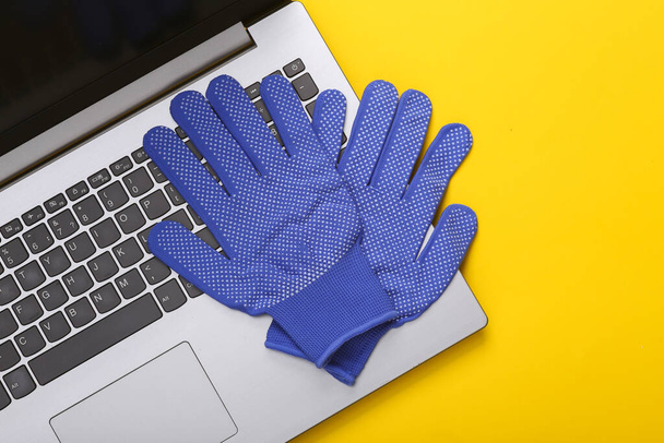 Laptop with work gloves on a yellow background. Top view - Photo, Image