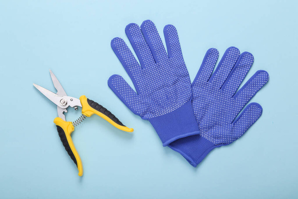Potatore da giardino con guanti da lavoro su sfondo blu. posare piatto. vista dall'alto - Foto, immagini