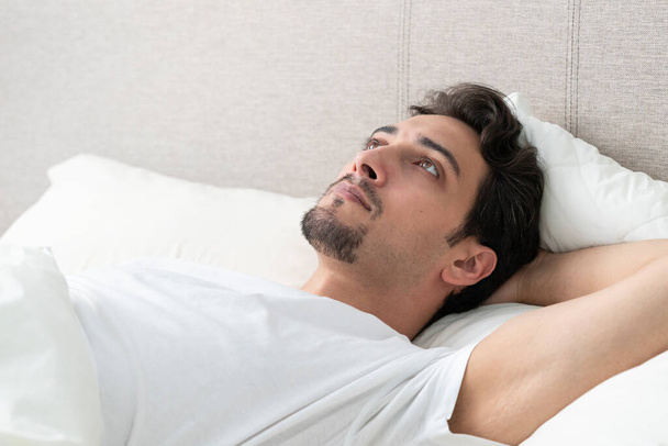 Продуманий красивий чоловік лежить в ліжку рано вранці
  - Фото, зображення