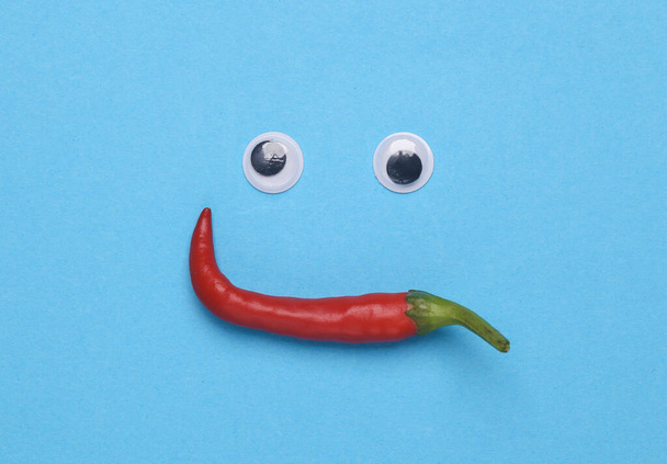 Kasvot tehty suojalasit silmät ja chili paprikat sinisellä taustalla - Valokuva, kuva