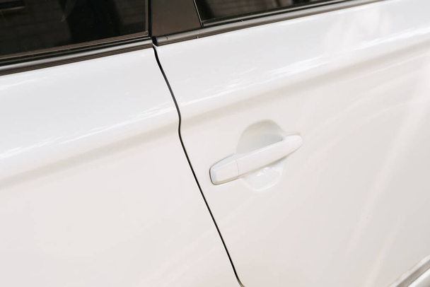 Nahaufnahme eines neuen weißen modernen Autos mit schlüssellosem Griff vor der Tür. - Foto, Bild