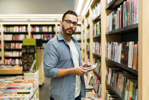 Portrait of a handsome caucasian man reader shopping at the book shop and buying novels  - Photo, Image