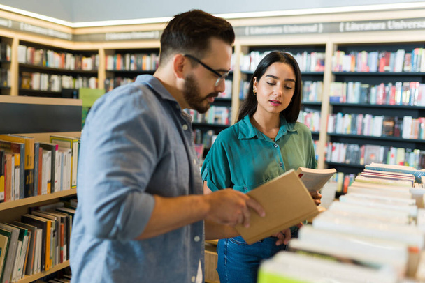 Aantrekkelijke blanke man flirten met een mooie vrouw tijdens het winkelen voor boeken in de boekwinkel - Foto, afbeelding