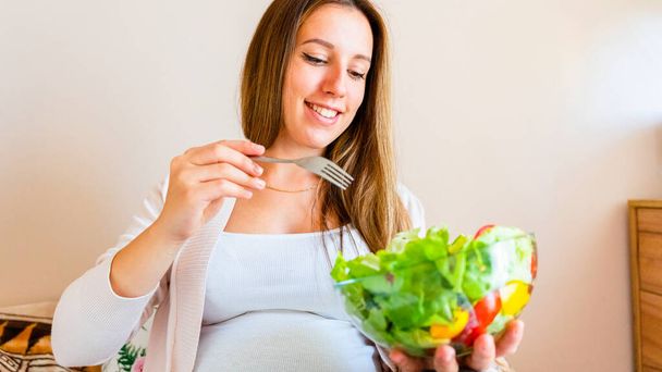 Pregnancy eating healthy salad. Happy pregnant woman eating nutrition food. People lifestyle food concept - Valokuva, kuva