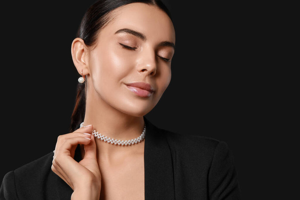 Young woman with elegant pearl jewelry on black background, space for text - Fotoğraf, Görsel