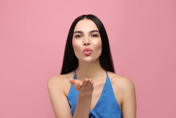 Beautiful young woman blowing kiss on pink background - Foto, Imagem